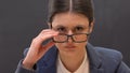 Strict school principal angrily looking through eyeglasses, educational process