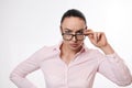 Strict and serious woman in business casual clothes, looking at the camera through lowered glasses. Isolated portrait on white