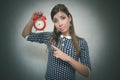 Strict woman boss with red alarm clock on gray background.