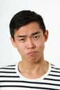 Strict young Asian man making face and looking at camera