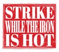 STRIKE WHILE THE IRON IS HOT, text on red stamp sign Royalty Free Stock Photo