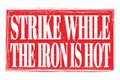 STRIKE WHILE THE IRON IS HOT, words on red grungy stamp sign Royalty Free Stock Photo