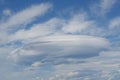 A striking, circular cloud formation is visible against a bright blue sky filled with soft white clouds. This unusual Royalty Free Stock Photo