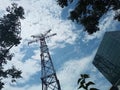 Tower Touching the Sky - Amidst Modern Buildings: A Green Oasis Under the Cloudy Blue Sky