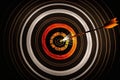 Archery target with orange center with arrow striking bullseye, on dark background Royalty Free Stock Photo