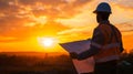 A striking image of a worker holding a blueprint against the backdrop of a rising sun symbolizing the beginning of a new Royalty Free Stock Photo