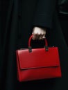 Striking red handbag contrasted against a black coat in a chic ensemble.