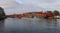 Red steel Python Bridge spanning the water in Amsterdam\'s Eastern Docklands. Royalty Free Stock Photo