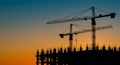Construction Site Silhouette at Sunset Two Tower Cranes and Building Under Construction AI generated. Royalty Free Stock Photo