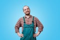 striking studio portrait, a young smiling bearded worker with arms on hips looking at camera