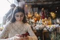 A striking, vibrant young woman checking out New Year& x27;s decorations with her smartphone. Royalty Free Stock Photo