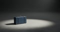 A single dusty blue suitcase rests in the spotlight Royalty Free Stock Photo