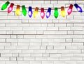 String of Color christmas light bulbs on white brick background Royalty Free Stock Photo