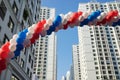 String of colorful balloons against apartment buildings and blue sky on background. Concept of outdoor celebration activities or e Royalty Free Stock Photo