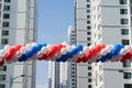 String of colorful balloons against apartment buildings and blue sky on background. Concept of outdoor celebration activities or e Royalty Free Stock Photo