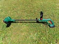 String electric lawnmower, trimmer, green plastic body, placed on the grass Royalty Free Stock Photo