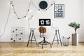 String lights with bulbs on a white wall in a stylish workspace interior for a student with herringbone parquet floor. Real photo.