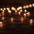 String lights with small, warm white bulbs are arranged on a dark, textured surface. Royalty Free Stock Photo