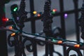 String of multicolor Christmas lights on antique iron fence