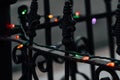 String of multicolor Christmas lights on antique iron fence