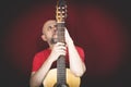 String musical instrument. Mature charismatic male guitarist. guy with beard holds guitar. bearded man in a red shirt