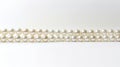 String of pearls on white background. White and round pearls with iridescence. Pearls decrease in size towards the ends Royalty Free Stock Photo