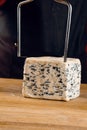 String for slicing blue cheese. Mix of cheeses on plate. Slicing dorblu, gorgonzola, roquefort. French gourmet cuisine.