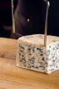 String for slicing blue cheese. Mix of cheeses on plate. Slicing dorblu, gorgonzola, roquefort. French gourmet cuisine.