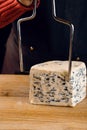 String for slicing blue cheese. Mix of cheeses on plate. Slicing dorblu, gorgonzola, roquefort. French gourmet cuisine.