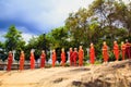 A string of statues of Buddhist monks in orange tones in a Buddhist temple in Sri Lanka