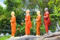 A string of statues of Buddhist monks in orange tones in a Buddhist temple in Sri Lanka