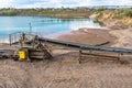 A string of transport belting in a gravel pit for transporting gravel and sand over long distances, belts go along the lake.