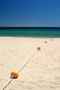 String of yellow buoys on sunny, sandy beach Royalty Free Stock Photo