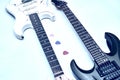 Two guitar, neck fretboard mediators plectrum on a pale blue.Black, white