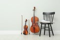 Stringed and wind musical instruments near white wall indoors, space for text