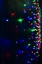 Strings of blue, red and green holiday lights in the dark as a background. Photo in perspective with selective focus