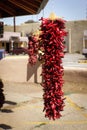 Strings of dried red pepers hanging outdoors in southwest USA adobe town - selective focus