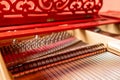Strings inside a red grand piano. Piano playing, dampers, felt hammers, bronze strings and metal frame. Royalty Free Stock Photo