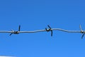 A strip of barbed cold wire on a perishable blue sky. Barbed wire fence. Prohibited zone Royalty Free Stock Photo