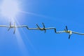 A strip of barbed cold wire in a perishable blue sky. Rays of the sun. Barbed wire fence. Prohibited zone, restriction of freedom. Royalty Free Stock Photo