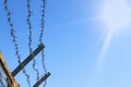 A strip of barbed cold wire in a perishable blue sky. Rays of the sun. Barbed wire fence. Prohibited zone, restriction of freedom. Royalty Free Stock Photo