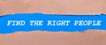 A strip of blue paper with the inscription FIND THE RIGHT PEOPLE between the brown paper. View from above