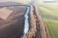 A strip of colorful trees and a strip of snow on black land. Drone view Royalty Free Stock Photo