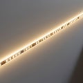 A strip of LED lights is embedded in a smooth, white wall, emitting a warm, ambient Royalty Free Stock Photo