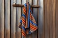 a striped beach towel hanging on a rusty nail on a weathered wooden wall