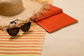 Striped beach towel, hat, book and sunglasses on sand, closeup Royalty Free Stock Photo