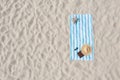 Striped beach towel with straw hat, book, sunglasses and slippers on sand, aerial view. Space for text Royalty Free Stock Photo