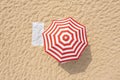 Striped beach umbrella near towel on sand, aerial view Royalty Free Stock Photo