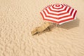 Striped beach umbrella near wooden sunbed on sandy coast Royalty Free Stock Photo