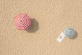 Striped beach umbrellas, towel, hat and flip flops on sandy coast, aerial view Royalty Free Stock Photo